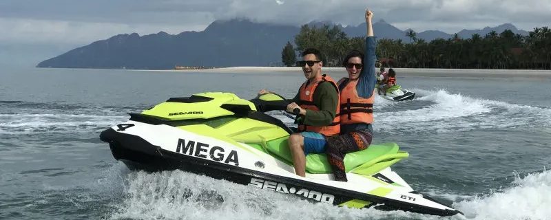 Two people riding a bright yellow and green jet ski on water.