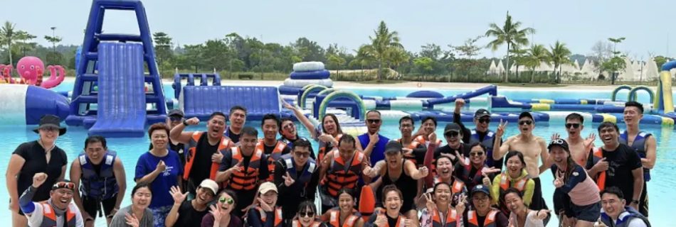 Group of people in life jackets posing at a water park with inflatable attractions.