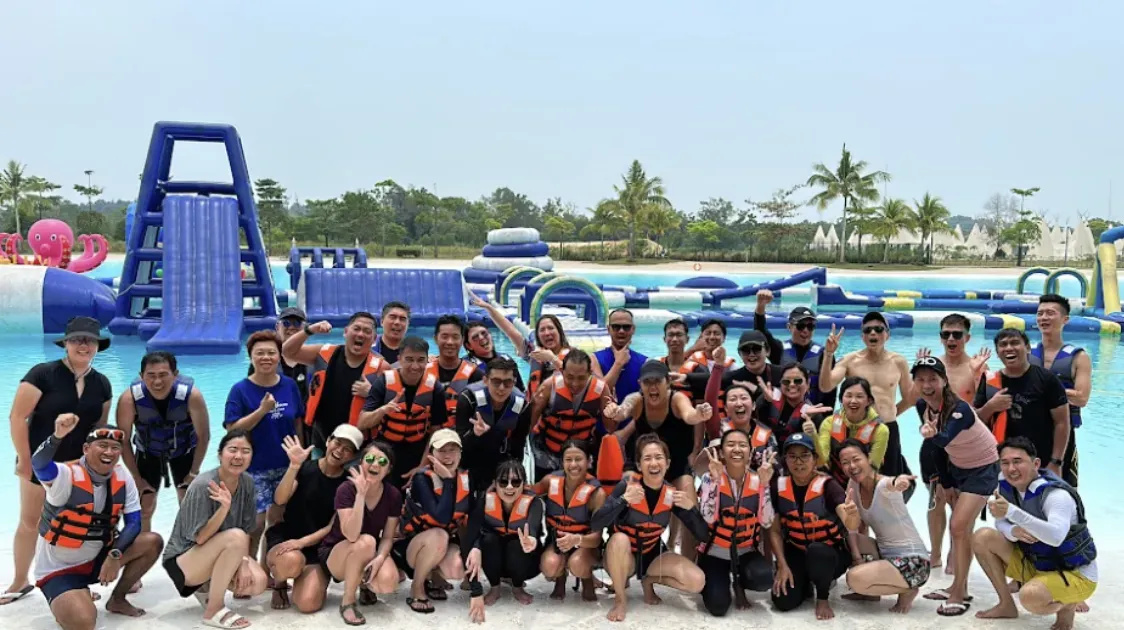 Group of people in life jackets posing at a water park with inflatable attractions.