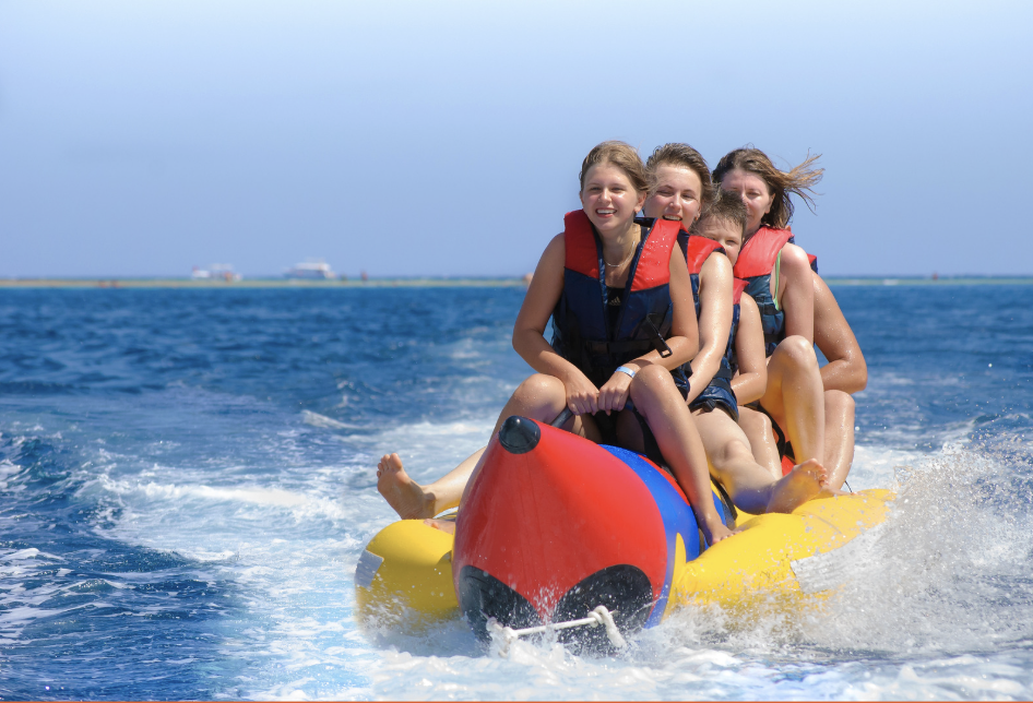 Group of smiling people enjoying a Banana Boat ride on the turquoise waters of Bintan,